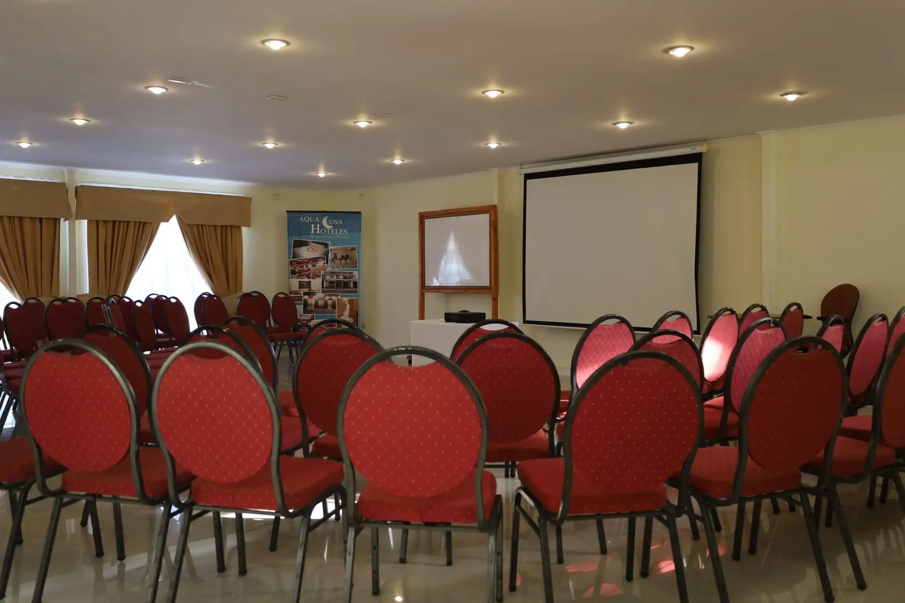 Sala de reuniones con sillas tapizadas, telón y pizarra