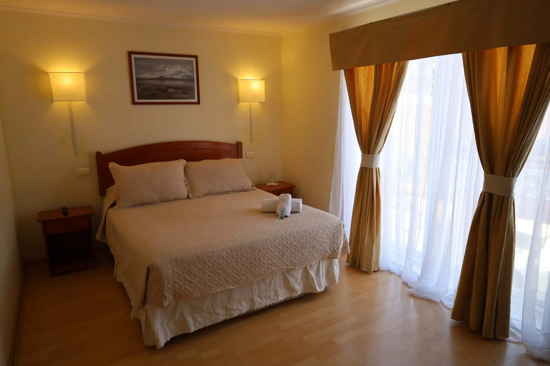Habitación doble con cama matrimonial y ventanal con cortinas