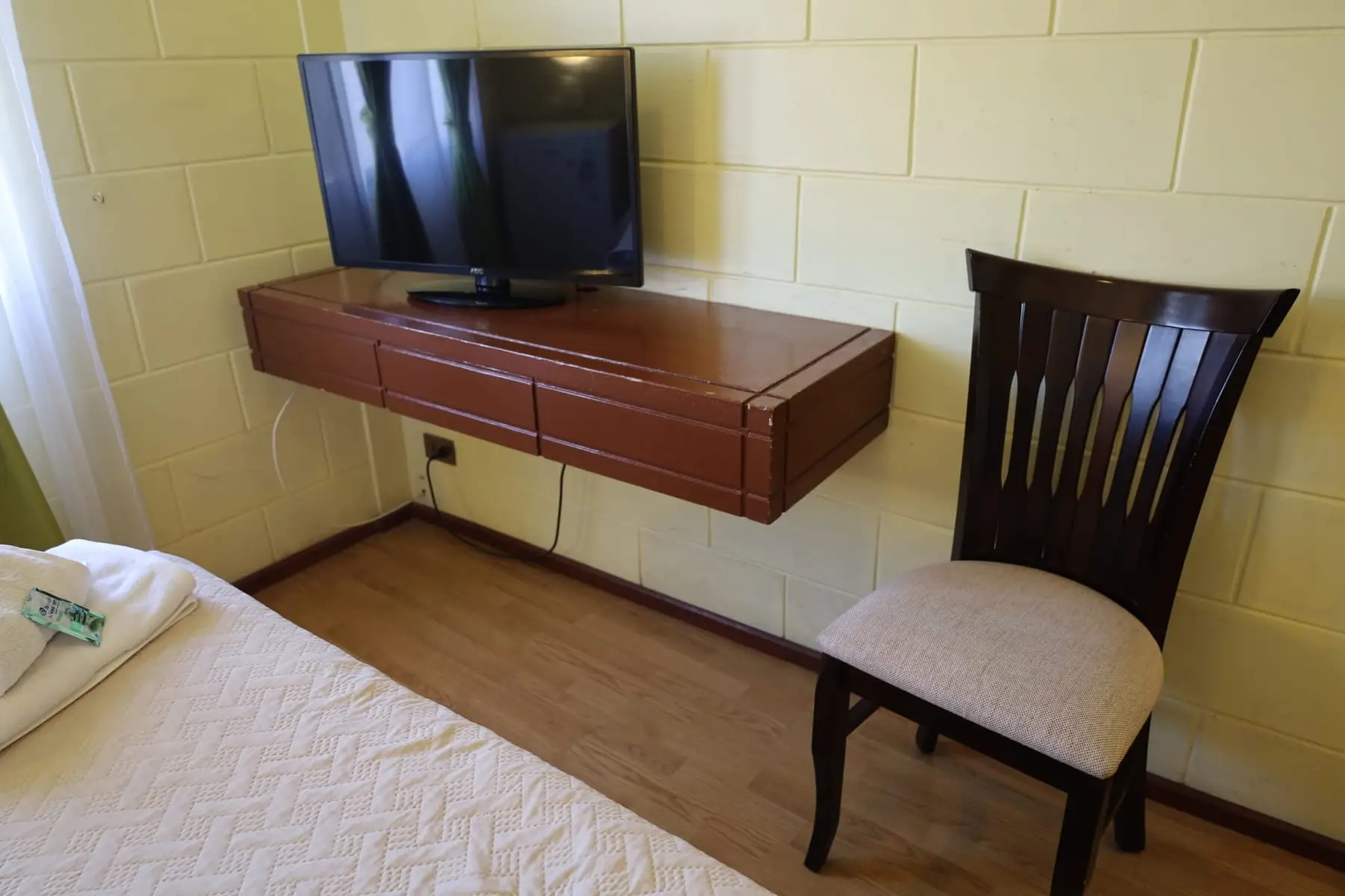 Mueble con televisor y silla junto a la cama