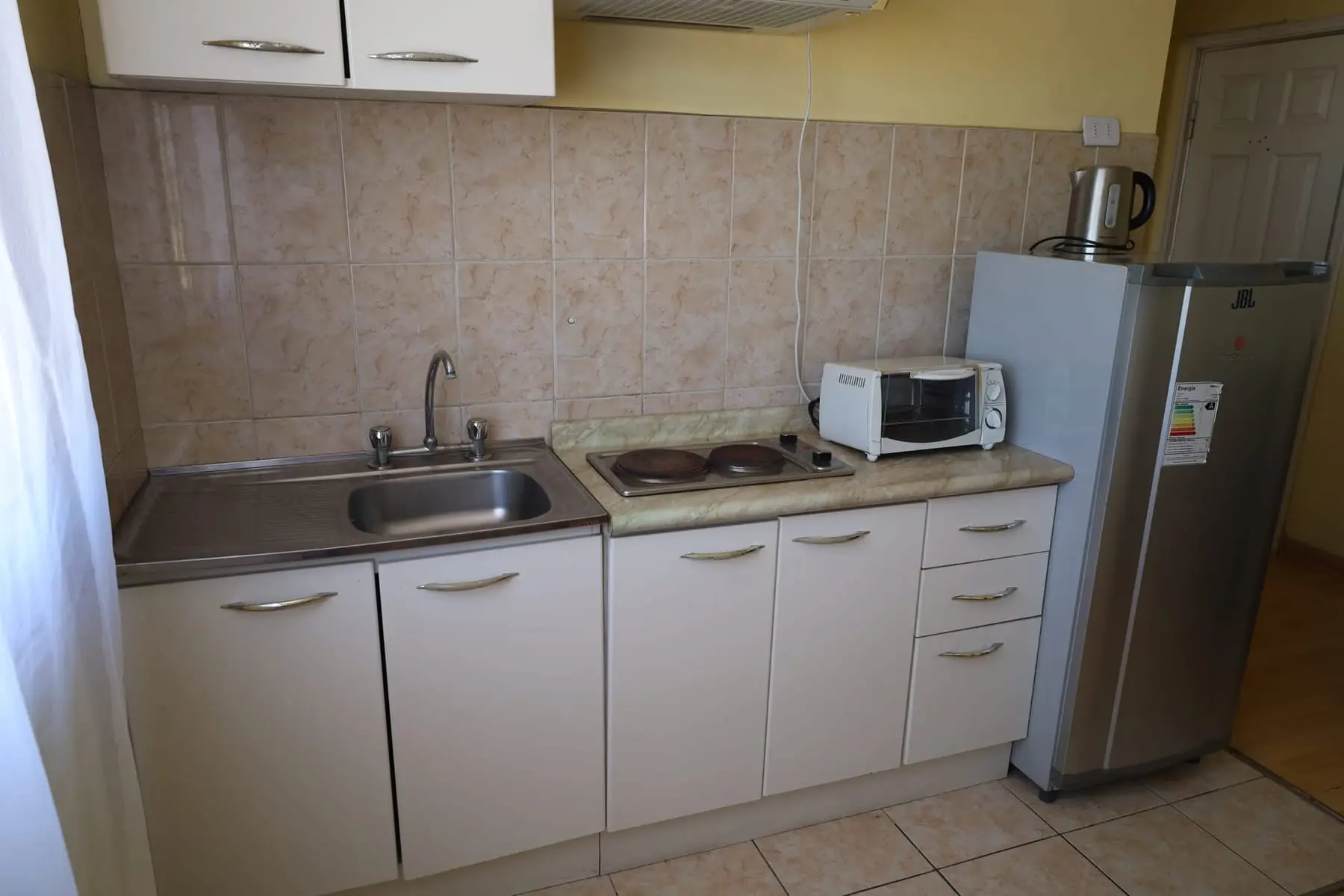Cocina con lavaplatos, encimera eléctrica, horno eléctrico y refrigerador