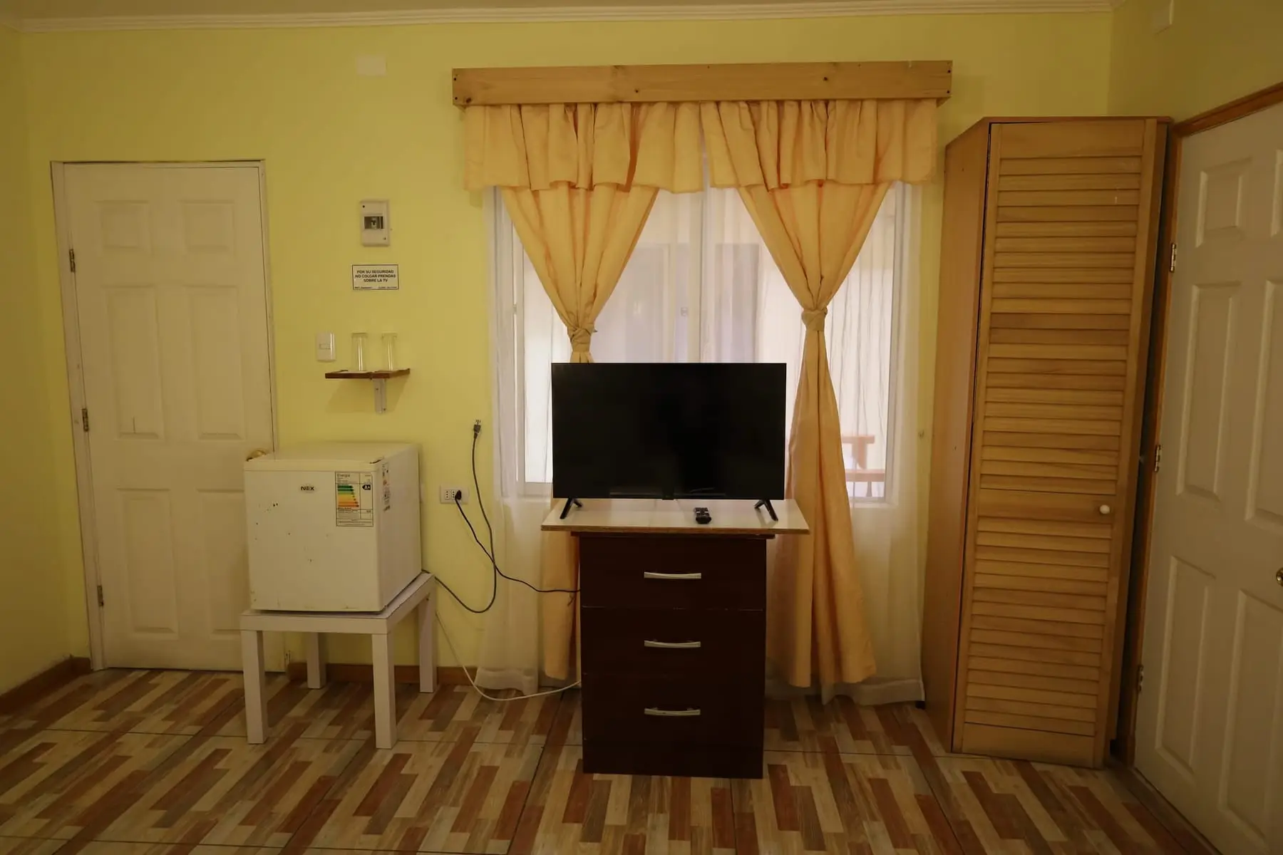 Televisor, frigobar, cómoda y clóset en la habitación triple