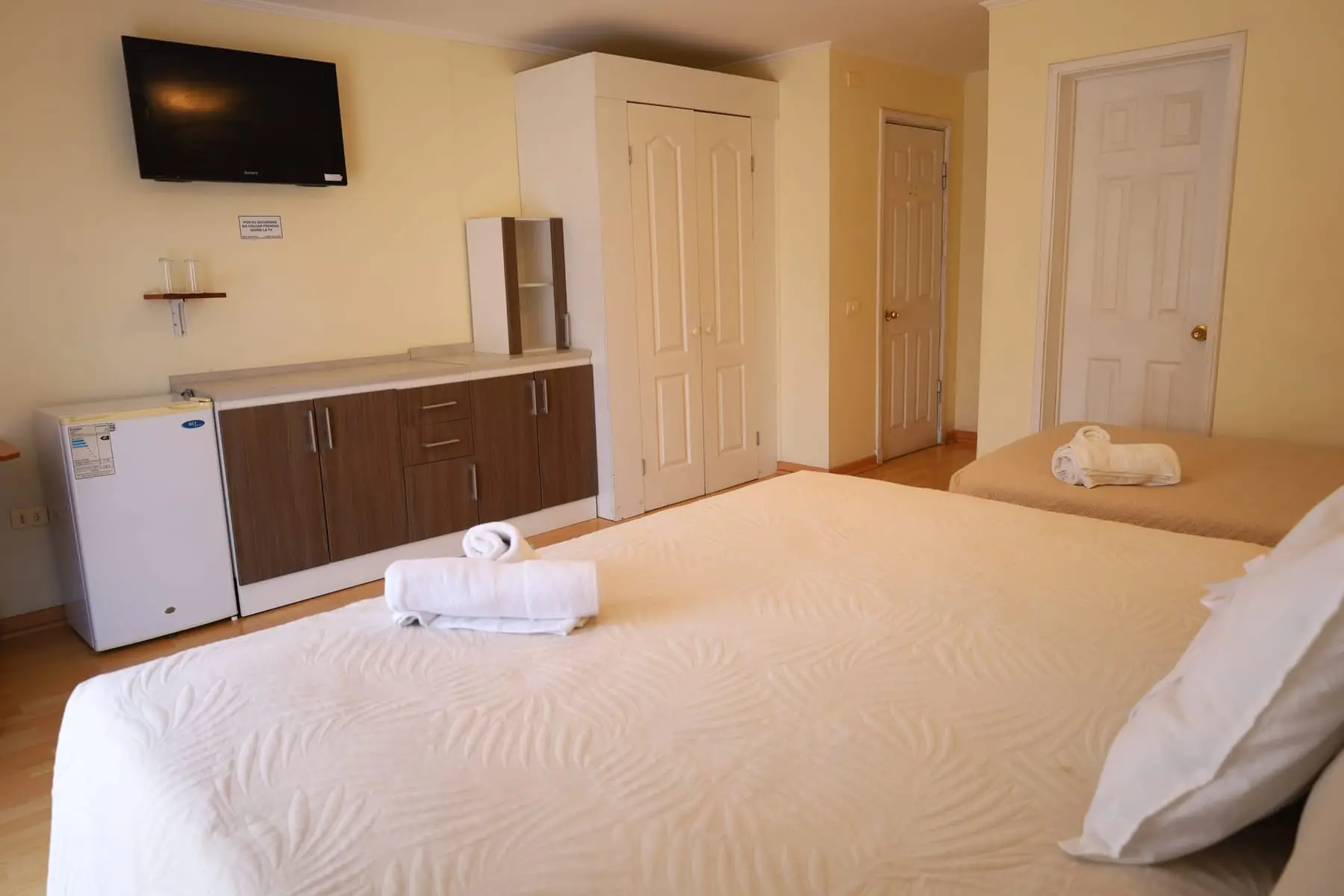 Habitación amplia con televisor, mueble, clóset y frigobar