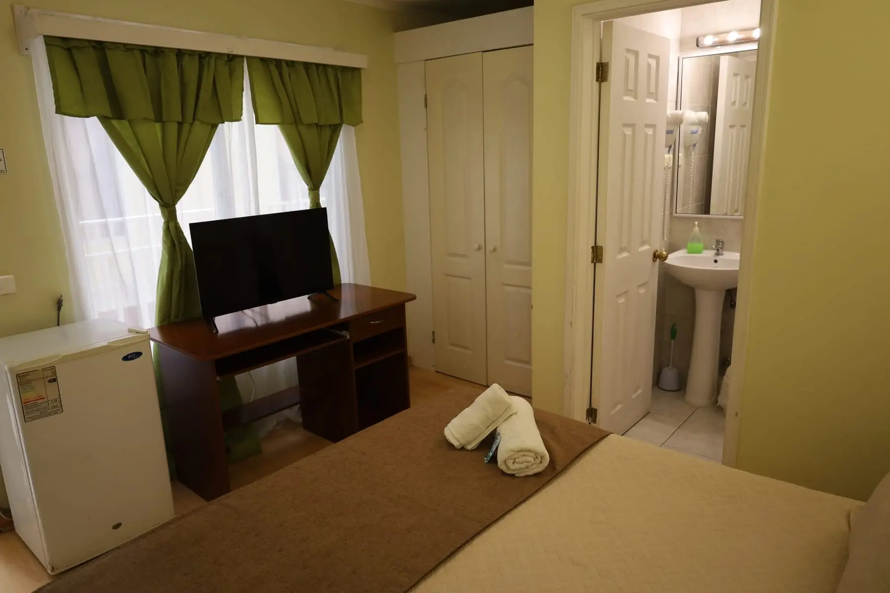 Escritorio con televisor, frigobar y acceso al baño