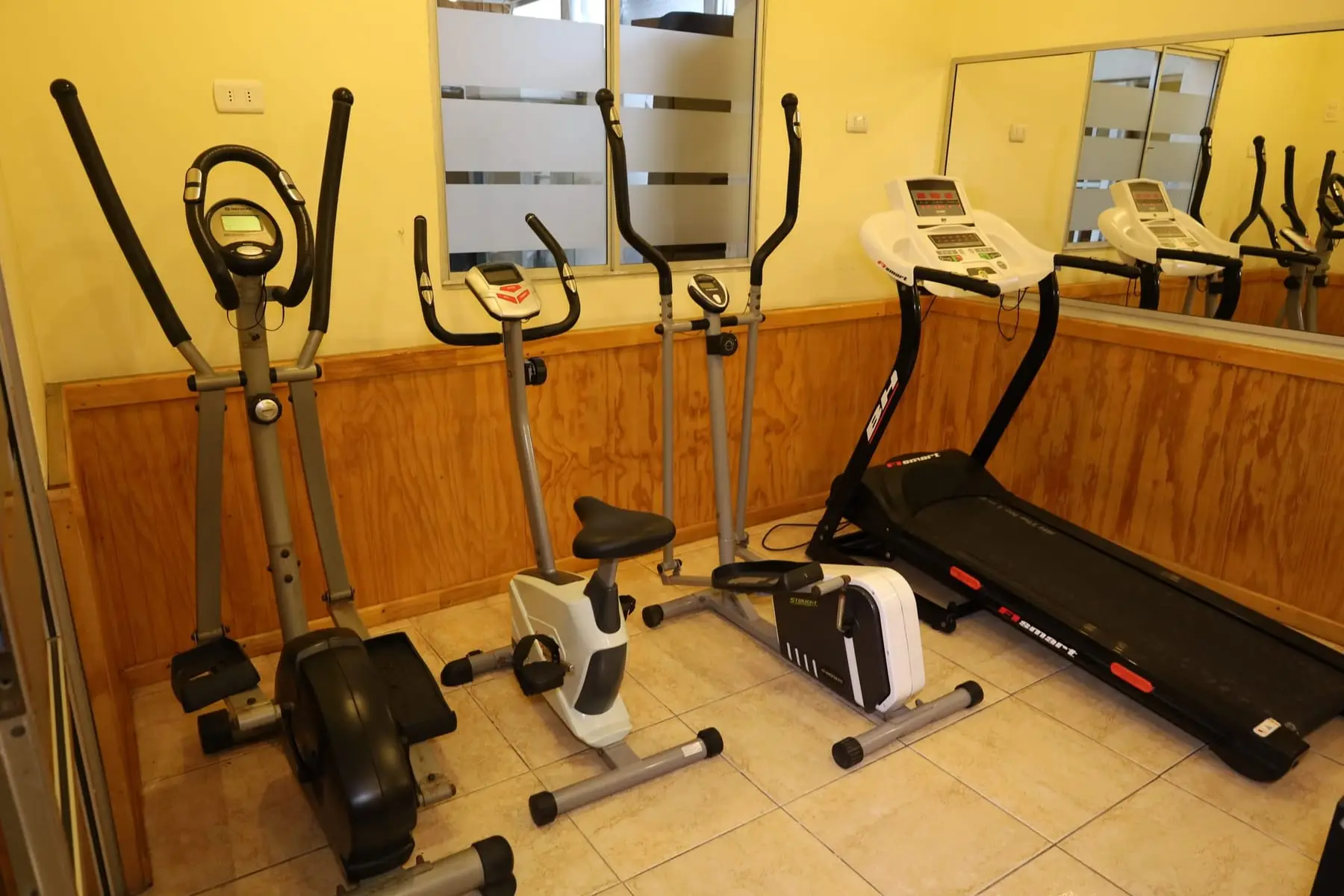 Gimnasio con trotadora, bicicletas estáticas y elípticas