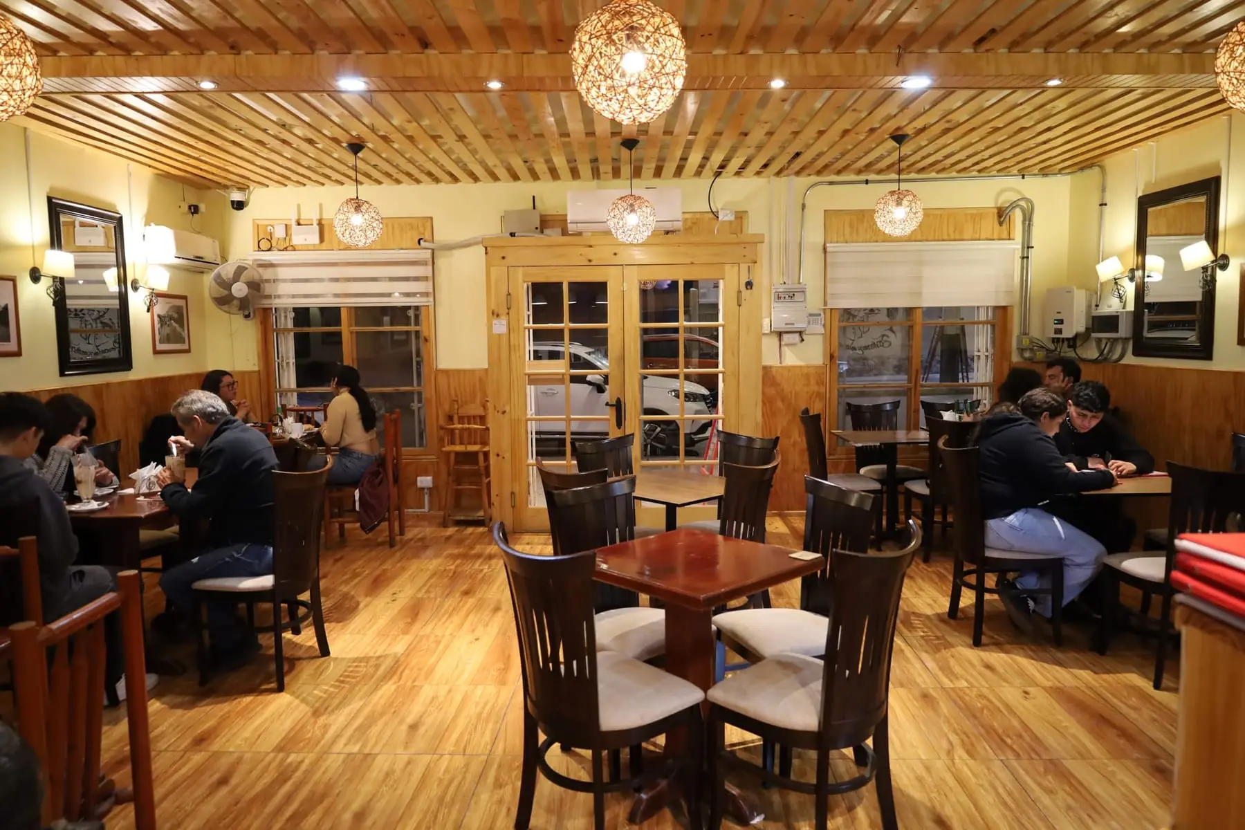 Salón de Aqualuna Café con piso de madera y lámparas de mimbre