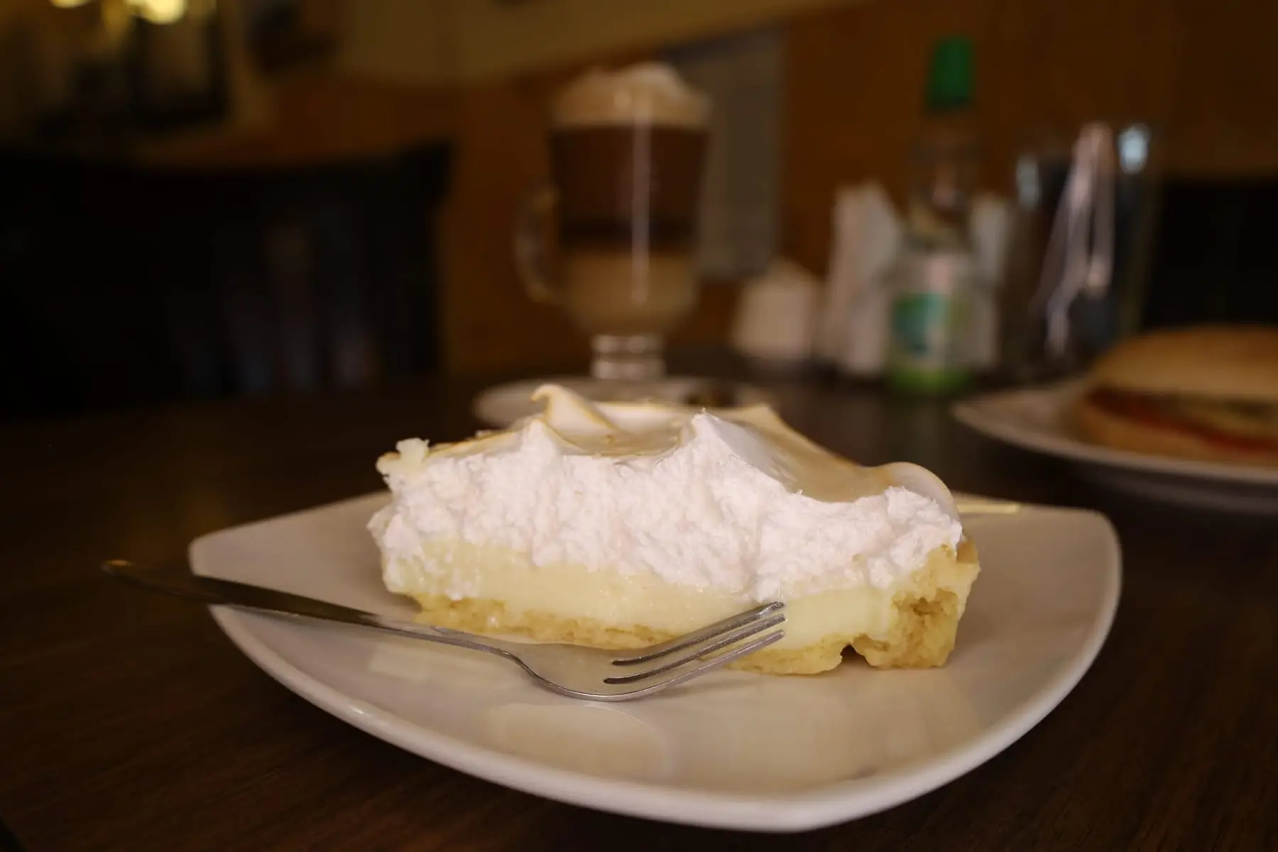 Trozo de pie de limón con un café al fondo