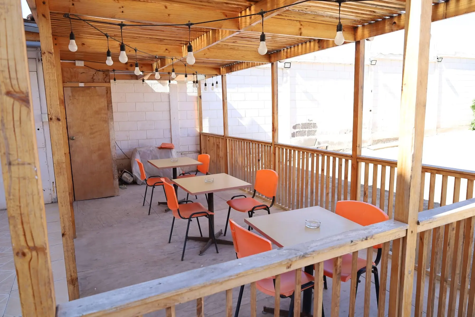 Terraza techada con pérgola de madera y luces colgantes